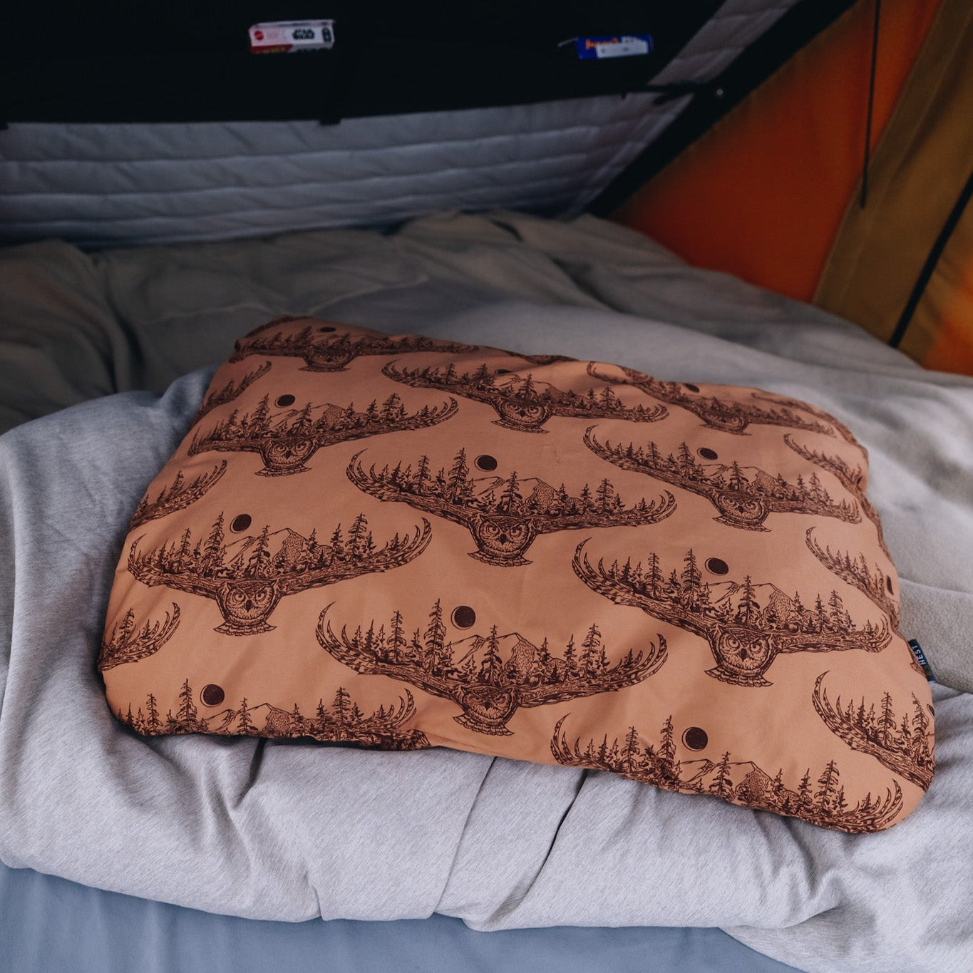 An image of a HEST x Super Pacific custom pillowcase and pillow inside the tent of a Super Pacific truck bed camper.