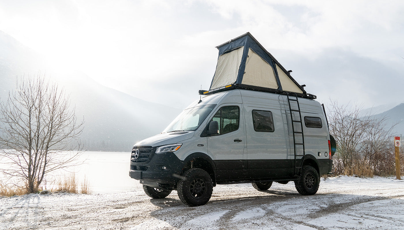 Mercedes Sprinter van with CloudCap van poptop tent is parked on a snowy dirt road.