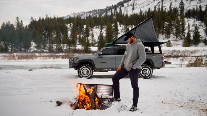 Hunter Pauley stands next to a campfire in front of his Super Pacific equipped Toyota Tacoma.