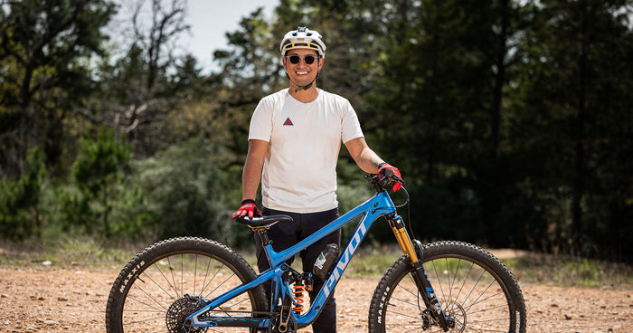 Ryan Magsino stands with his mountain bike in the Texas dirt.