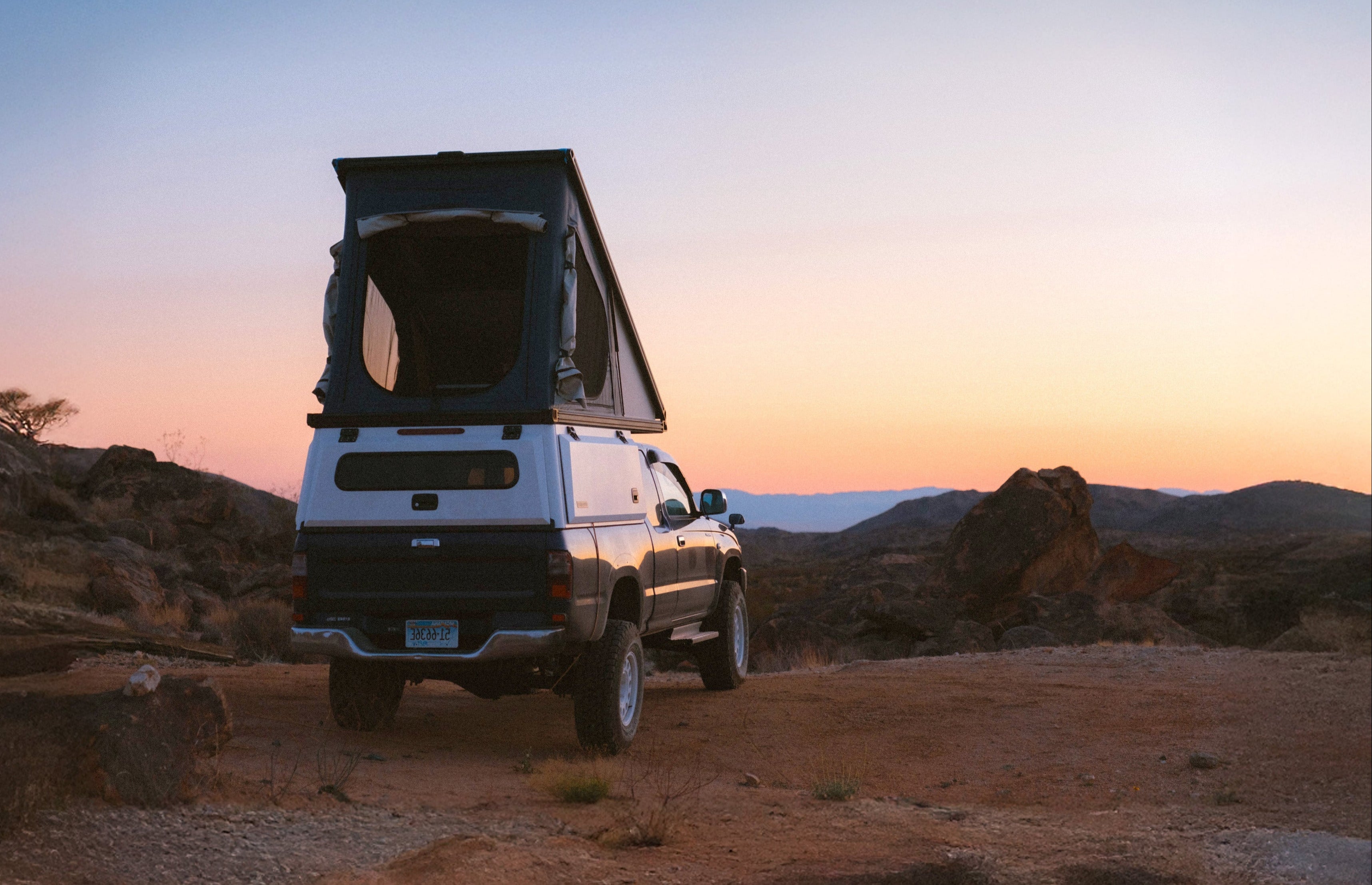 Toyota truck with an X1 Camper parked in a desert landscape at sunset