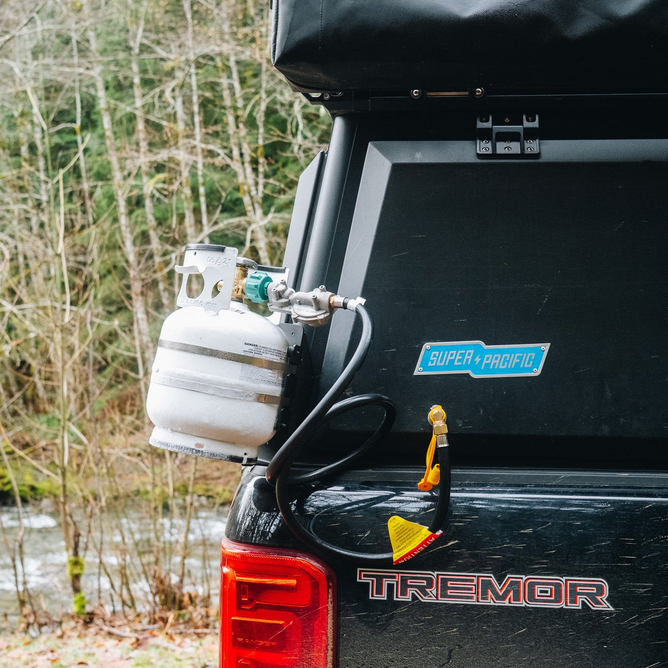 Propane tank attached to the back of a Super Pacific X1 Camper with a forest background.